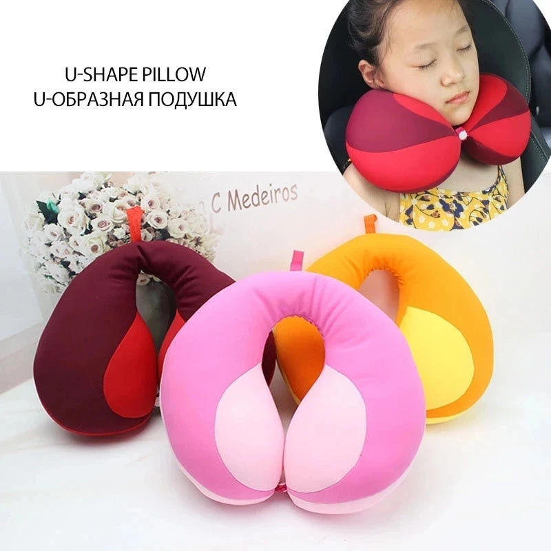 U-shaped travel pillows in red, pink, and yellow on a white surface with a child using one of them.